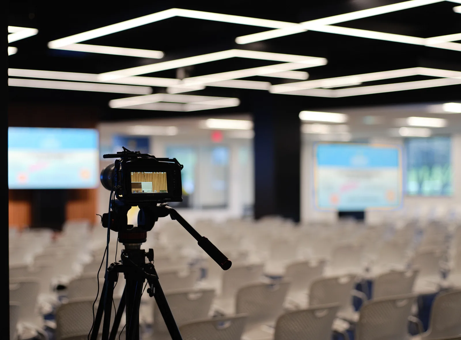 Conference room setup — camera on tripod with dual LED screens
